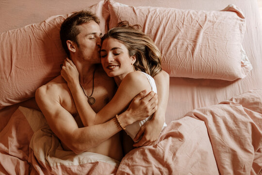 Happy young couple lying in bed