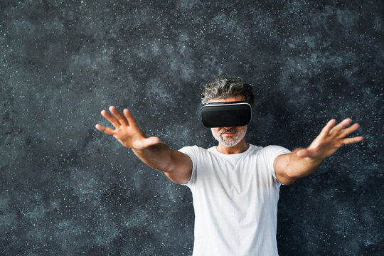 Mature man wearing VR glasses reaching out with hands