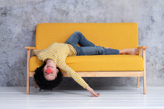 Boy with red clown nose and black hair on yellow couch