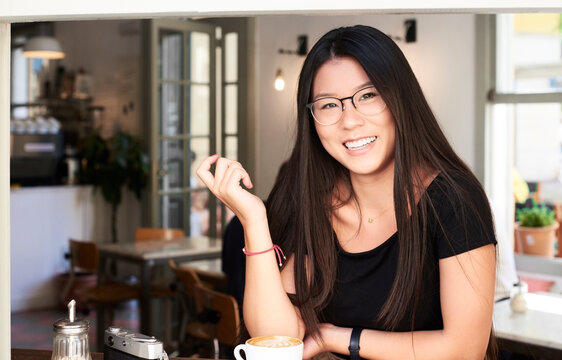 Asian young woman smiling at camera in a coffee shop