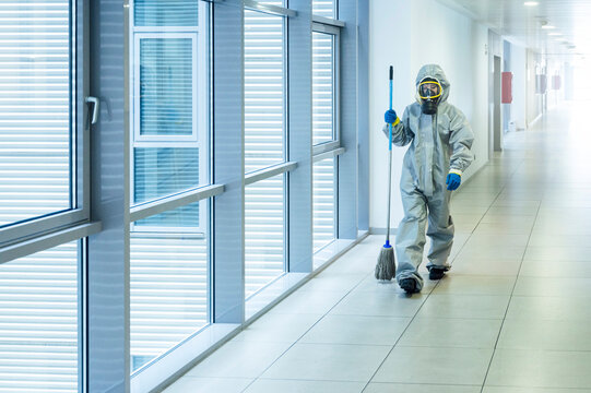 Cleaning staff walking with cleaning mop in corridor, wearing protective clothing