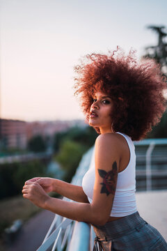 Portrait of young woman standing on terrace at evening twilight