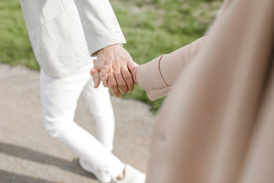 Strolling young copule holding hands, partial view