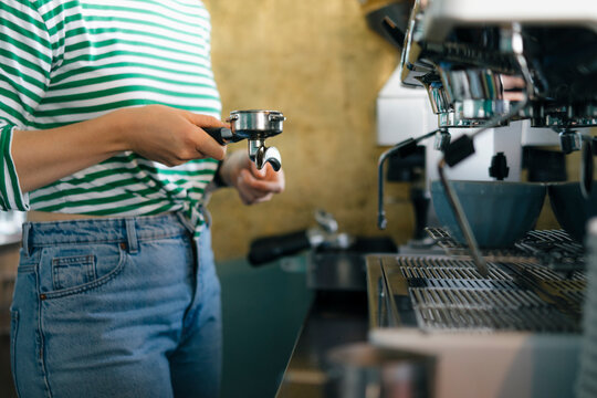 Close-up of young woman preparing coffee in a cafe