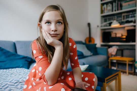 Portrait of serious girl sitting on couch at home