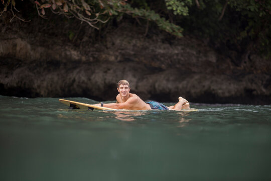 Indonesia, Java, man lying on surfboard on the sea
