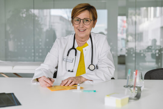 Portrait of smiling doctor filling out immunization card