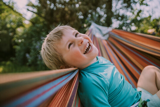 Cheerful boy relaxing on hammock at garden during sunny day