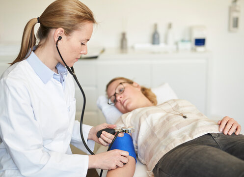 Female doctor taking blood pressure of patient in medical practice