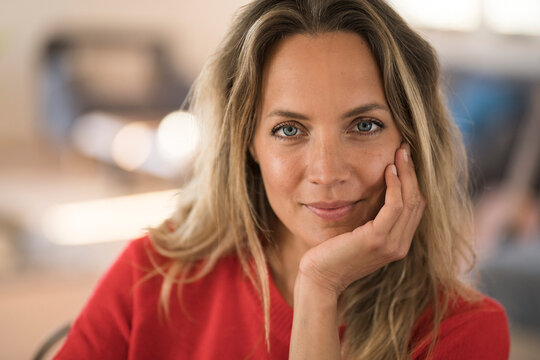 Portrait of smiling blond woman resting her head on the hand