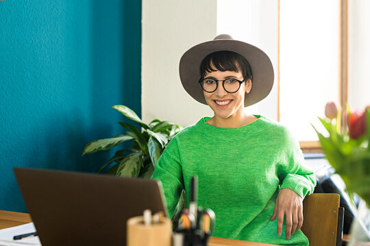 Portrait of happy businesswoman in home office working at her laptop