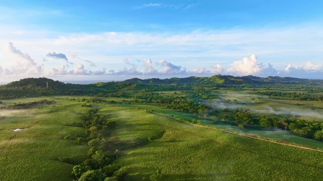A drone view of a mountain range bathed in morning fog. Forested foothills under a cloudy sky. Stunning aerial view of a tropical mountain landscape with lush pastures. Dominican Republic.