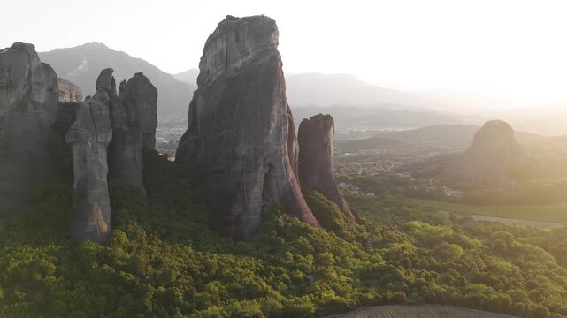 Majestic sandstone pillars and lush valleys of Meteora under soft glow of setting sun.