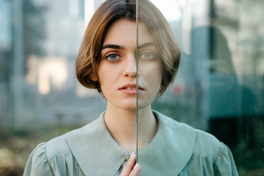 Portrait of woman with half of her face behind a glass