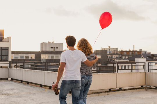 Back view of young couple on roof terrace at evening twilight