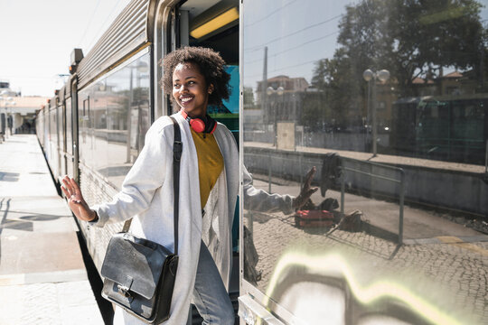 Smiling young woman entering a train