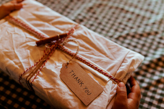 Hands of boy holding Christmas present at on table home