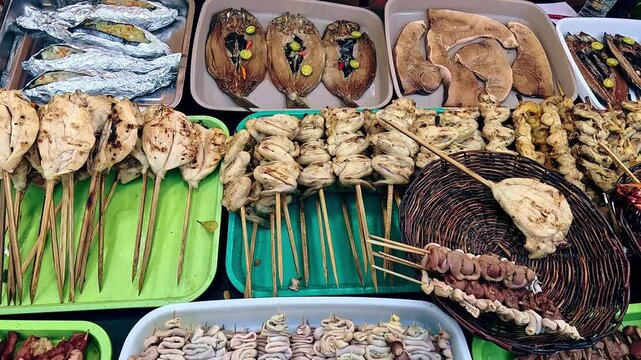 Overhead view handheld motion panning right to show a full display of different inihaw or skewers for grilling at a Filipino street food stall. Kabankalan, Negros Occidental, Philippines