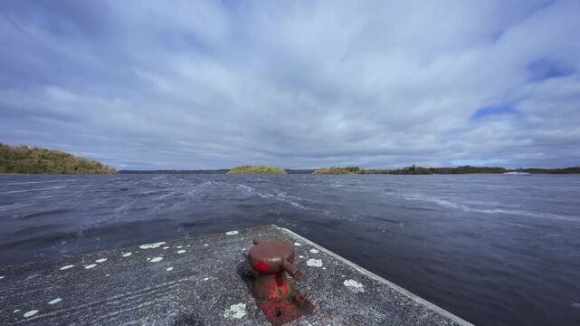 Time lapse of a concrete lake pier area with forest in distance on a mostly cloudy day at Lough Key in county Roscommon in Ireland.