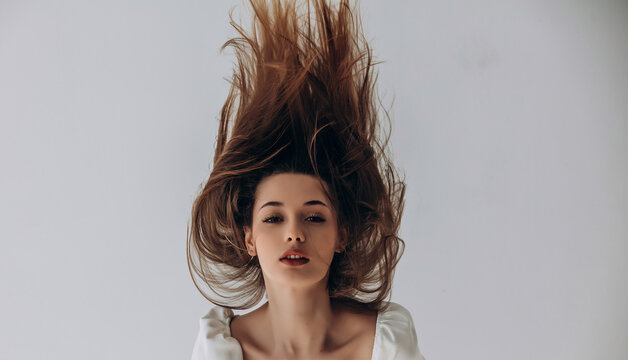 Beauty portrait of a model, a beautiful brunette girl with straight long hair in a white dress, healthy and natural on a white background