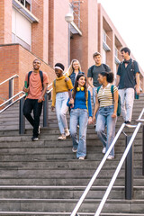 Obraz premium Diverse group of young students walking down urban university stairs together, enjoying college life and education
