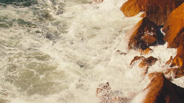 Closeup view, Crashing waves creating huge splashes.  Slow motion: Ocean Waves at high tide roll in and crash against coastal cliffs, huge rocks.  Big Sea waves crashing against the coastline rocks.