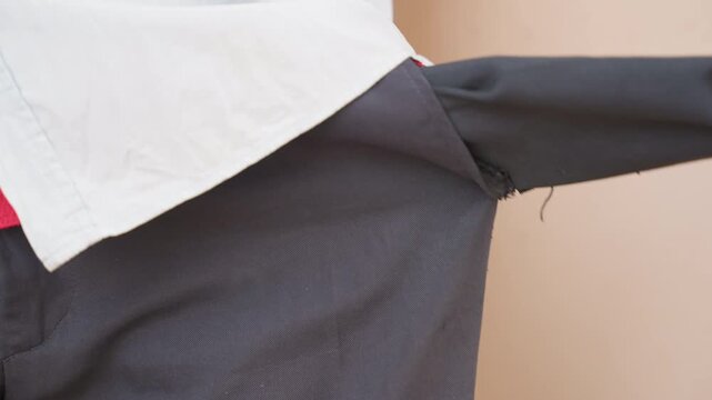 Man pulls empty pocket to check side closeup showing red shirt hem and frayed fabric, zipper detail and waist gesture, casual domestic scene suggesting chore or wallet search, mood of budget concern