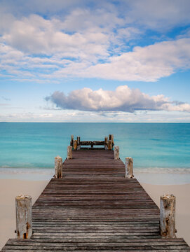 Looking down wooden pier on beach into the Caribbean ocean.
