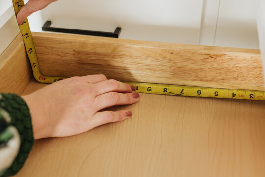 Woman uses tape measure to measure the inside of kitchen drawer