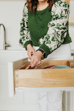 Woman uses tape measure to measure the inside of kitchen drawer