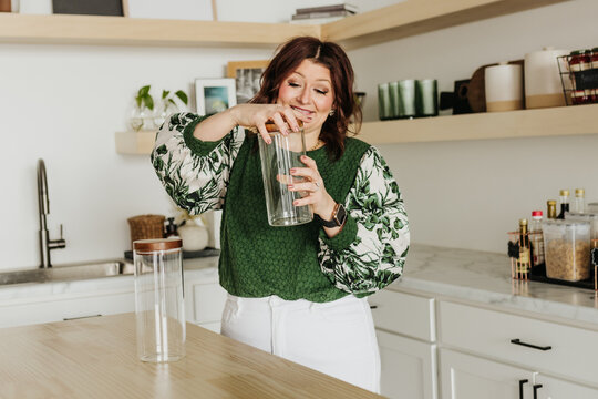 Woman screws lid on empty glass jar while standing in kitchen