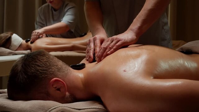 Relaxing hot stone back Couples massage therapy for couple lying on spa tables with professional therapists creating a soothing wellness and relaxation experience