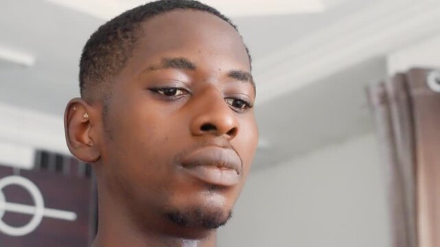 Black male against black painting cinematic mood, actor rehearsing monologue with melancholic glances, close facial study, soft curtain light, emotional subtlety, rehearsal and performance roles