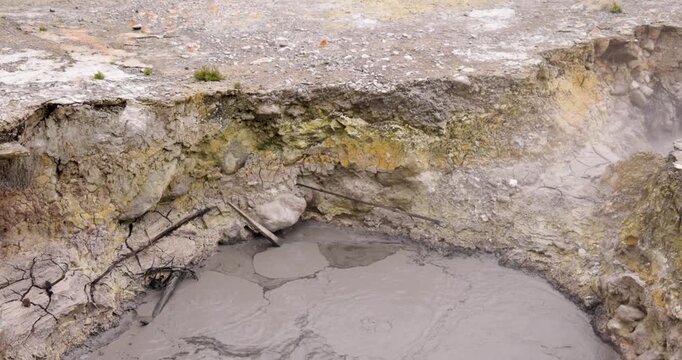 Volcanic pit with mud and boiling water with steam rising to the surface in a pond at Furnas, Azores.