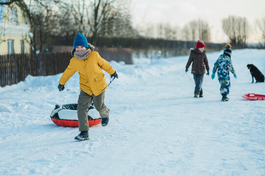 Children playing outdoors in winter pulling sleds through the snow