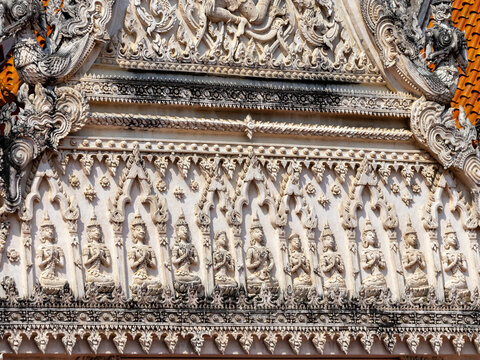 A detailed close-up of traditional Thai stucco bas-relief featuring a row of praying angels (Thep Phanom) on a temple roof.