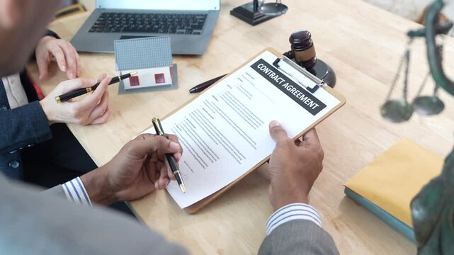 Lawyers reviewing a contract with a house model and gavel on the desk, representing real estate legal consultation, property agreement, and home ownership documentation.