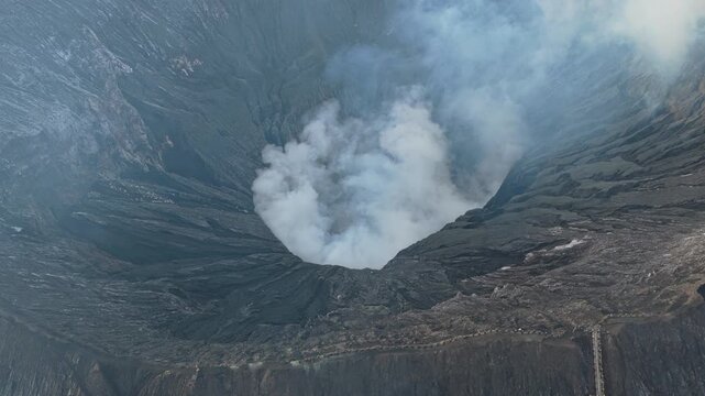 Majestic aerial view of the active bromo volcano crater in indonesia. Powerful smoke and gas plumes rise from the geological formation
