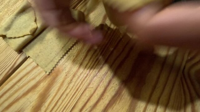 Hands shaping Chabakia dough into spirals and flower-like twists, showing intricate folding and layered patterns, highlighting traditional Moroccan pastry preparation before frying.