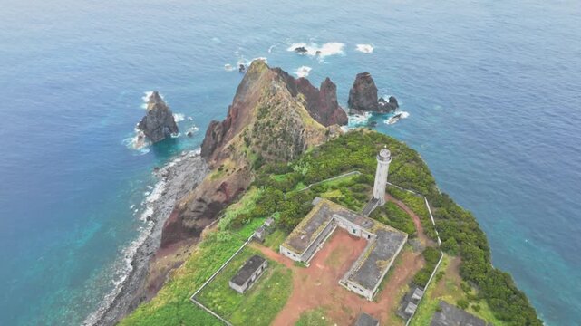 Farol dos Rosais lighthouse atop cliffs on S&atilde;o Jorge, Azores, Portugal, with dramatic sea stacks and Atlantic surf, cinematic aerial dolly reveal