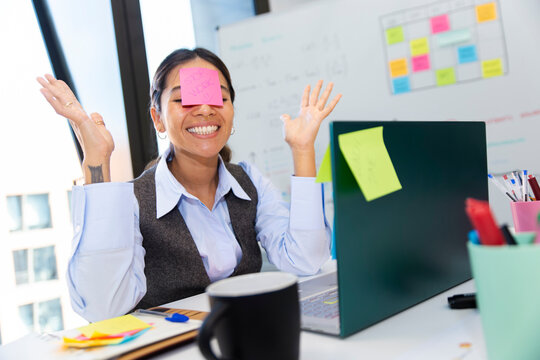 Manager enjoying playful work break with sticky notes at office desk