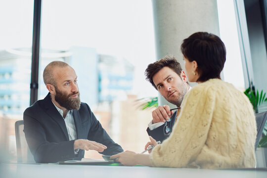 Colleagues discussing a contract in a modern office boardroom