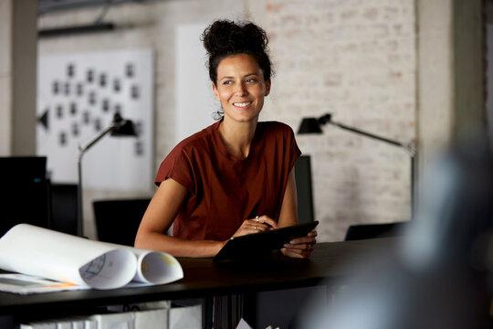 Smiling businesswoman architect working with tablet in creative office
