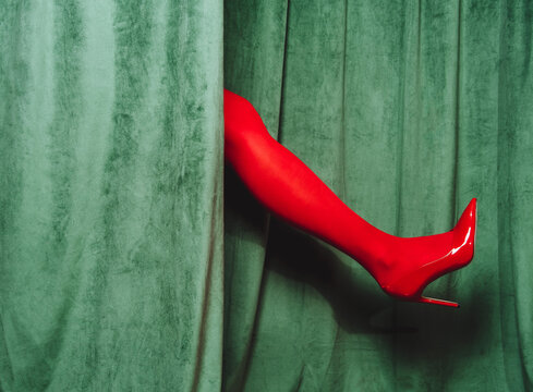 Red high heel leg emerges through green curtain in retro cabaret style