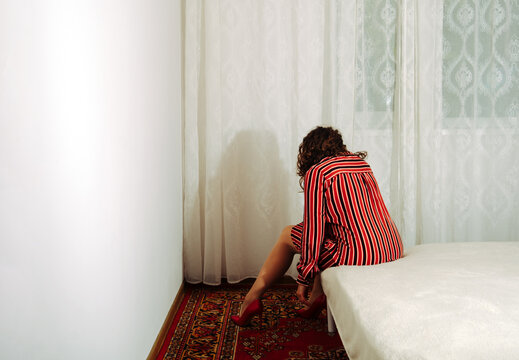Person in striped dress sitting in despair on carpeted floor indoors