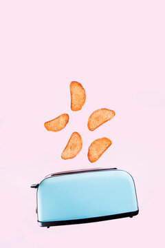 Blue toaster with toasted bread slices jumping on pastel pink background