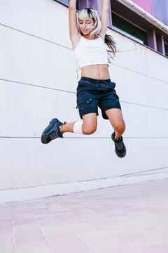 Jumping woman with alternative hairstyle in urban outdoor setting