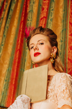 Woman in rococo vintage dress reading a book indoors