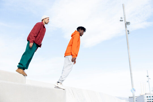 Two men leaning forward in mid-air during an urban parkour challenge