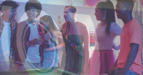 Laughing woman polka-dot dress and birthday sash chatting at party by pool table with balloons